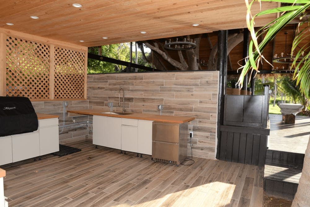 An outdoor kitchen with a grill under a covered patio