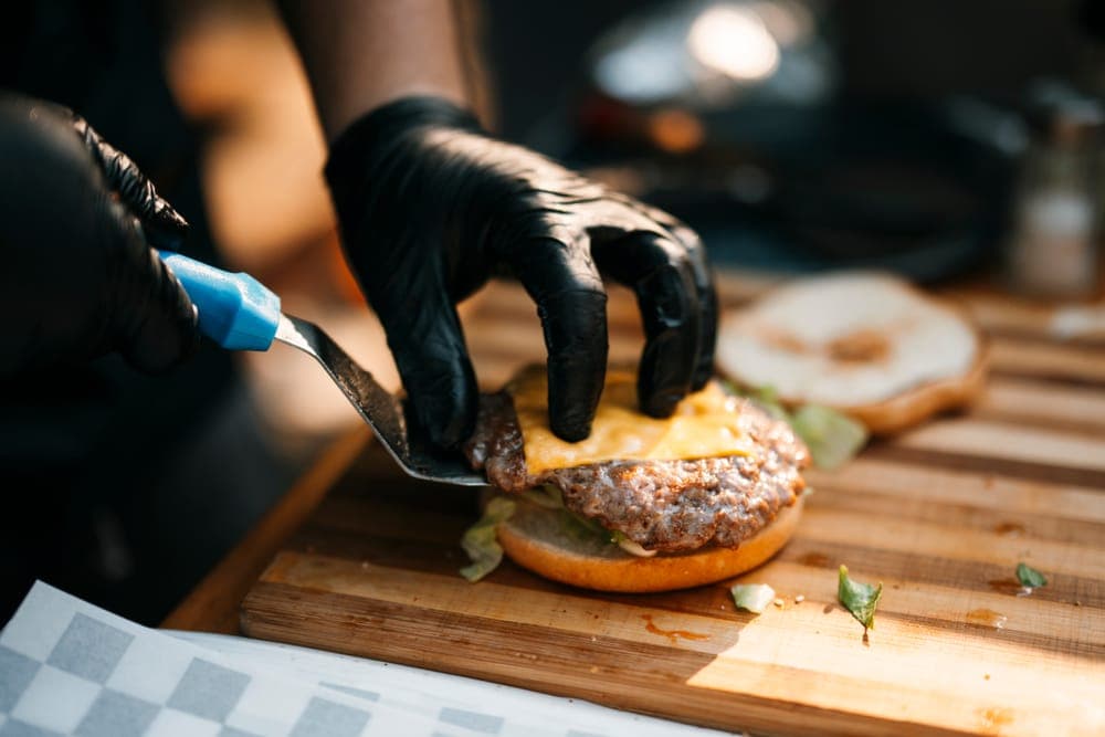 Grilling a cheeseburger wearing heat gloves