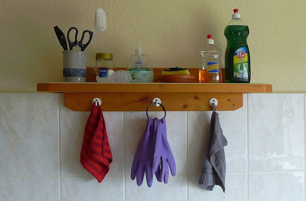 A kitchen shelf of cleaning and cooking utensils