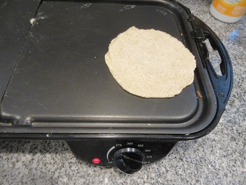A tortilla cooking on an electric griddle indoors
