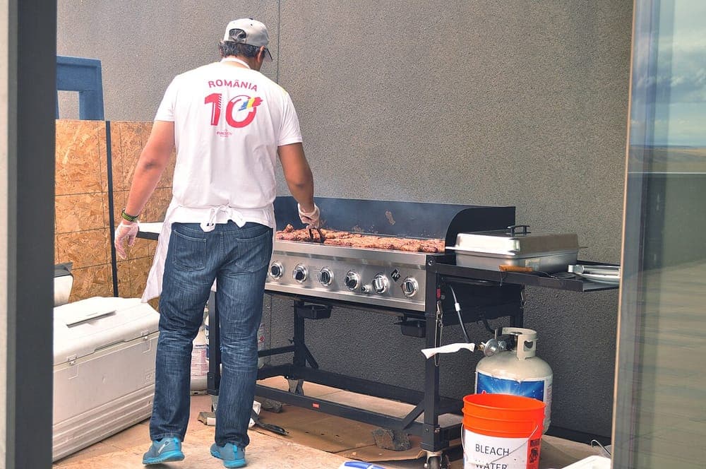 Sausages cooking in rows across a large outdoor griddle